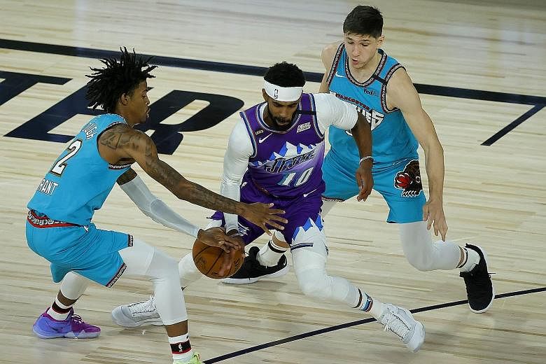 Mike Conley of the Utah Jazz comes up against the Grizzlies' Ja Morant (extreme left) as the Jazz clinched a 124-115 win at Disney World.