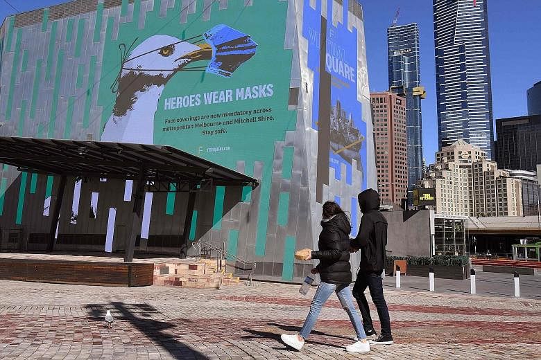 A mural in Melbourne's central business district urging people to wear a mask yesterday. Shops were shut and streets were deserted in the city of about five million people. Residents are still allowed to go out during the day for exercise and food, o