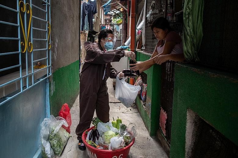 A government worker in a hazmat suit selling fresh produce in a neighbourhood in Navotas, Metro Manila, which is under a two-week lockdown starting from Tuesday. Philippines has recorded over 75,000 cases in June and July alone.