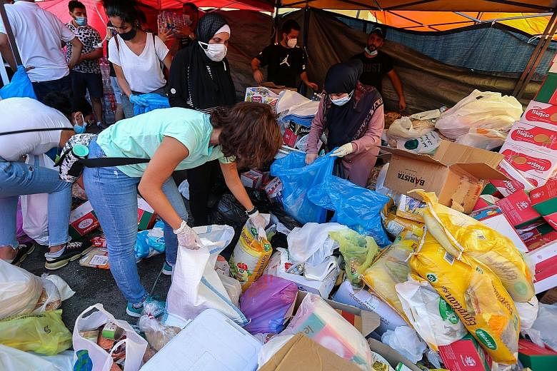 A spontaneous clean-up operation in a Beirut district hit by the explosion, which killed more than 130 people and wounded thousands. Anger against a government seen as corrupt and inefficient has risen. PHOTOS: REUTERS Volunteers packing aid supplies