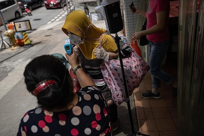 A foreign domestic worker getting her temperature checked before entering a wet market in Hong Kong yesterday. The health authorities yesterday reported 89 new confirmed Covid-19 cases, bringing the total tally of cases in the city to 3,938. PHOTO: E