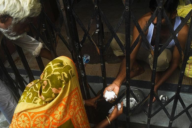 A man distributing food to homeless people in Kolkata, West Bengal, this week during a day-long lockdown imposed by the state government after a surge in coronavirus cases. PHOTO: AGENCE FRANCE-PRESSE