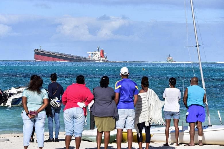 People in south-east Mauritius on Thursday looking at the stricken MV Wakashio, which is Japanese-owned but Panamanian-flagged. High waves have hampered efforts by the ship's operator, Mitsui O.S.K. Lines, to contain the fuel spill, and bad weather c