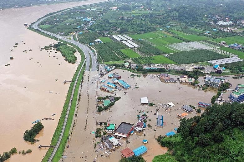 Left: A village submerged by overflow from the Seomjin River, due to two days of torrential rain in Hadong, South Gyeongsang province, in South Korea. Below: Residents waiting to be rescued from a market flooded by heavy rain in the south-eastern cou