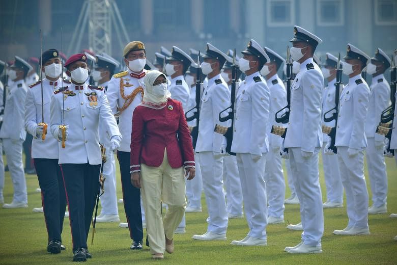 President Halimah Yacob inspecting the guard of honour at the Padang yesterday morning. Her silk cotton scarf and enamel brooch bore designs by two visually impaired artists.