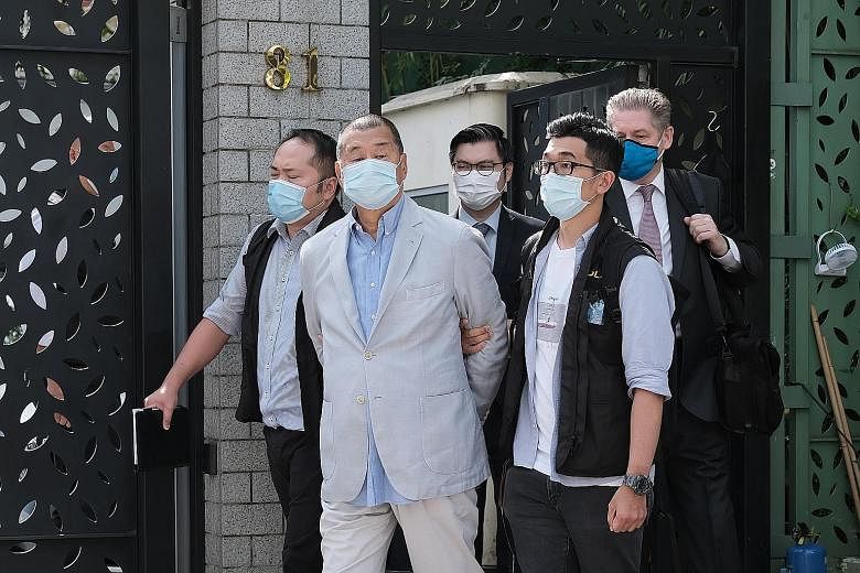 Hong Kong media tycoon Jimmy Lai being led away from his residence by law enforcement officials in Hong Kong yesterday. One of the city's most prominent democracy activists and an ardent critic of Beijing, Lai was taken to his office later in handcuf