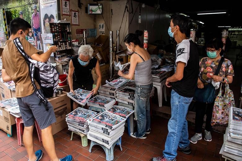 A vendor (second from left) selling copies of the Apple Daily at a newsstand in Hong Kong yesterday, a day after the city's authorities arrested the tabloid's owner. PHOTO: AGENCE FRANCE-PRESSE