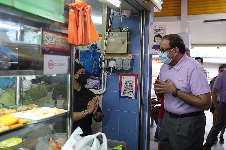 Communications and Information Minister S. Iswaran visiting hawkers at the Lorong 8 Toa Payoh Hawker Centre yesterday, where he said the increased adoption of the national unified e-payment solution was part of a larger mindset shift towards digitali