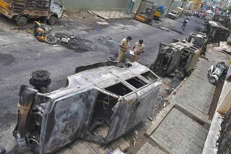 Burnt police vehicles on a street in India's Bengaluru yesterday. Violence broke out overnight in the city following a Facebook post that was offensive to Muslims sparked protests in which a police station was attacked, and a politician's house and v