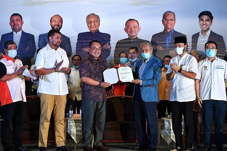 Tun Dr Mahathir Mohamad (in blue jacket) giving a letter of appointment on Wednesday to Mr Amir Khusyairi Mohamad Tanusi, who will be contesting the Aug 29 by-election in Perak. PHOTO: BERNAMA
