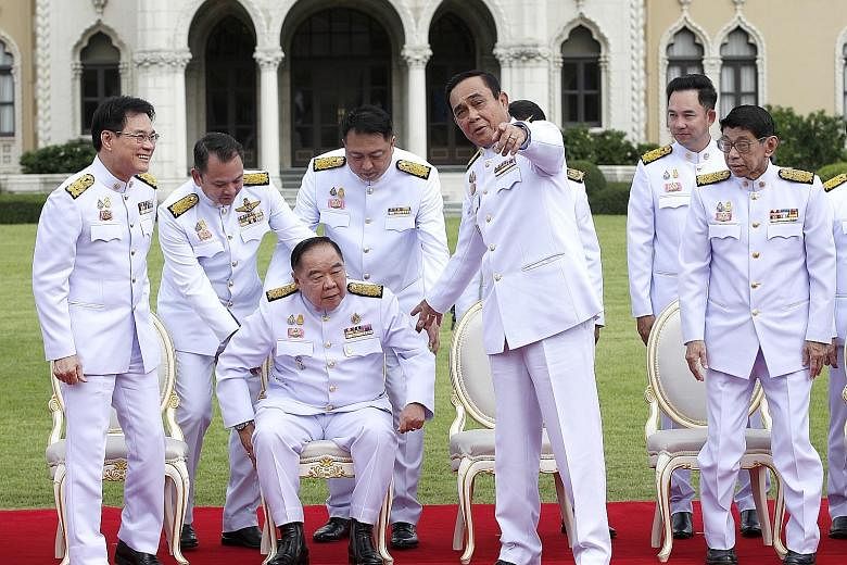 Thai Prime Minister Prayut Chan-o-cha pointing out something to Deputy Prime Minister General Prawit Wongsuwan (seated) during a group photo session after the Cabinet was sworn in yesterday. PHOTO: EPA-EFE