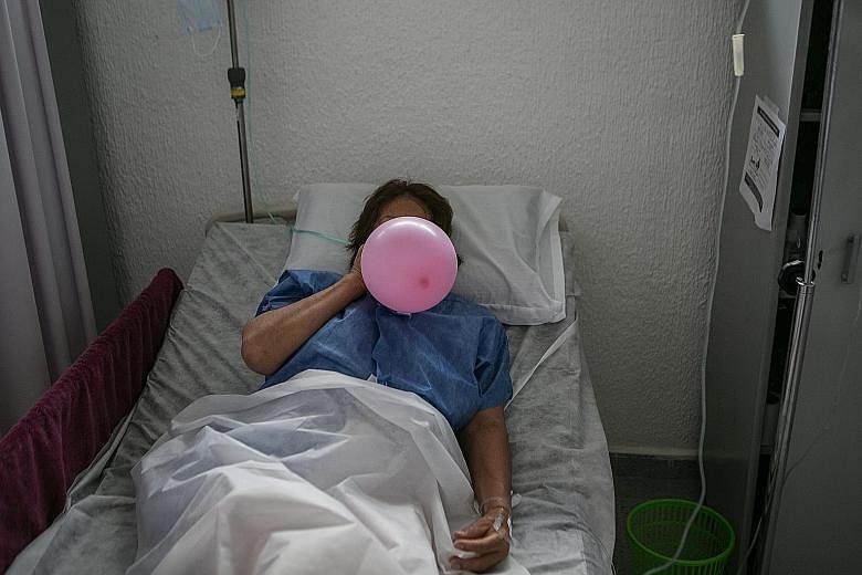 A patient using a balloon to strengthen her lungs as she recovered from Covid-19 at a makeshift hospital in Mexico City in June. A slum area being fumigated as a preventive measure against malaria and dengue in Mumbai, India. Lockdowns and supply-cha