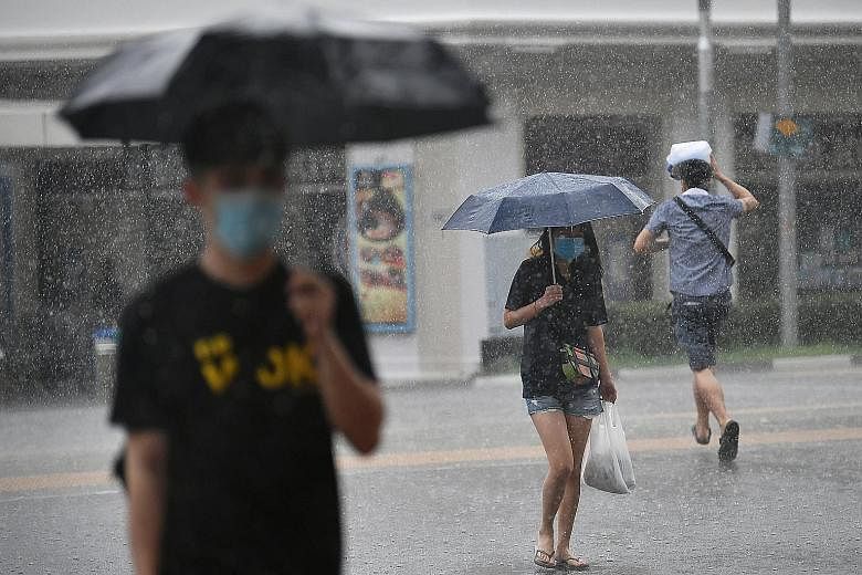 Pedestrians crossing the road amid heavy rain in Bugis yesterday. National water agency PUB said the downpour yesterday morning caused brief flash floods at the junction of Craig Road and Tanjong Pagar Road.