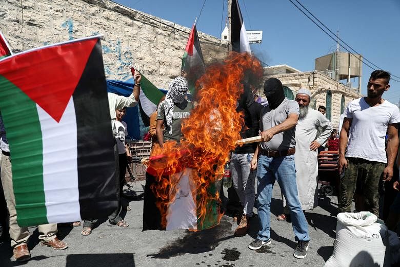 WEST BANK Palestinian protesters burning a United Arab Emirates flag yesterday in the city of Yatta in Hebron district. The Palestinian Authority has condemned the deal between Israel and the UAE as a betrayal of the Palestinian people.