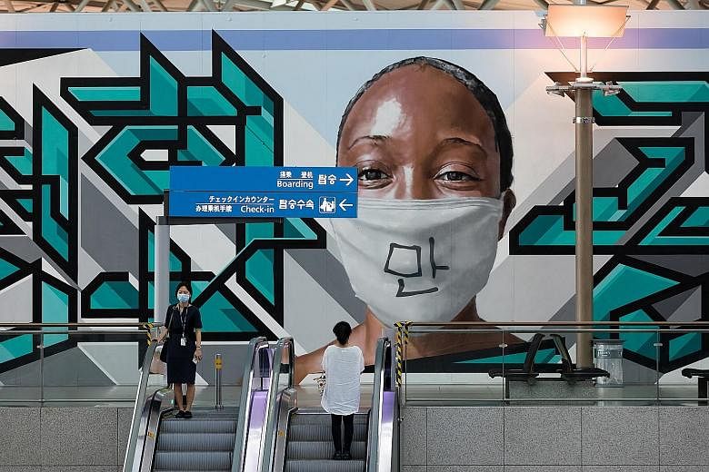 People riding escalators in front of a mural at Incheon International Airport in South Korea last week. Persistent outbreaks in recent weeks are threatening to undo the country's success in battling the coronavirus.