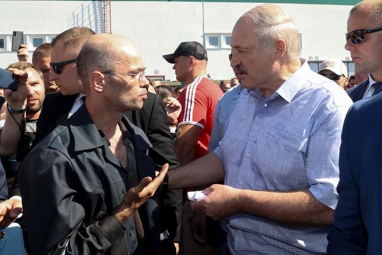 President Alexander Lukashenko (in light-coloured shirt) speaking to a worker at the Minsk Wheel Tractor Plant in the capital yesterday, amid mass protests and strikes as well as calls for him to step down. Pro-opposition Belarusians rallying in Mins