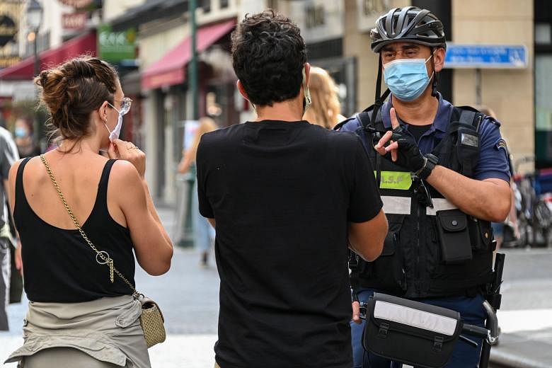 A police officer asking people to wear masks in Paris on Saturday. In France, an increase in new cases over the past week has prompted a push for new measures. PHOTO: AGENCE FRANCE-PRESSE Students practising social distancing at a high school in Germ