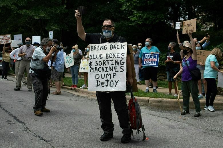 Protesters holding a demonstration in front of Postmaster General Louis DeJoy's home in Greensboro, North Carolina, on Sunday. Mr DeJoy has come under fire for changes made at the US Postal Service that could possibly hold up mail-in ballots in Novem