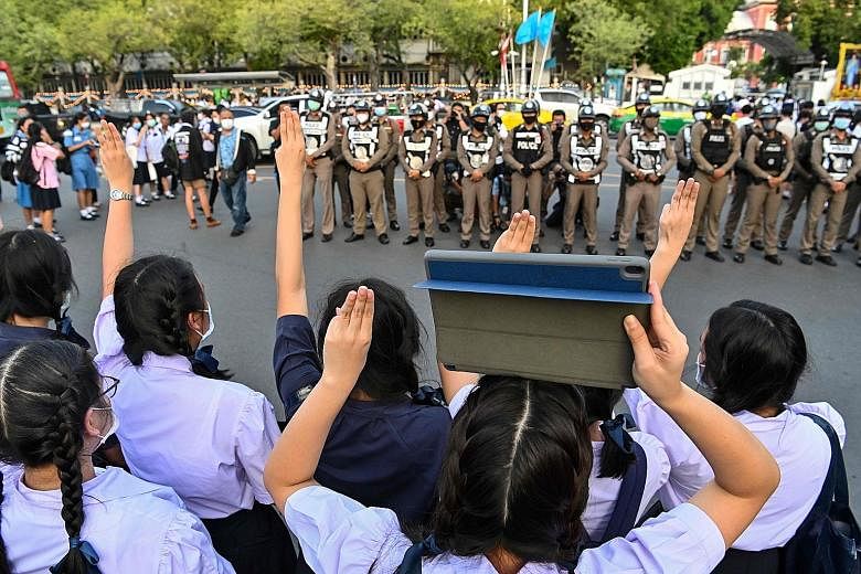 Pro-democracy students doing the three-fingered Hunger Games salute in front of police, during a rally in Bangkok yesterday. PHOTO: AGENCE FRANCE-PRESSE