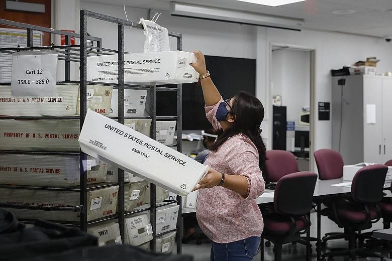 A worker holding US Postal Service bins with mail-in ballots in Florida on Tuesday, amid concerns that the agency's chief is hampering its ability to handle voting by mail. PHOTO: BLOOMBERG