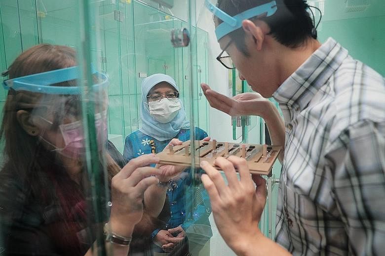 President Halimah Yacob observing visually-impaired sensory panellist Muhammad Zahier at work inside a diffusion booth with his sighted colleague Esther Tan during a visit to Firmenich's Global Perfumery Creative Centre at Science Park 1 yesterday.