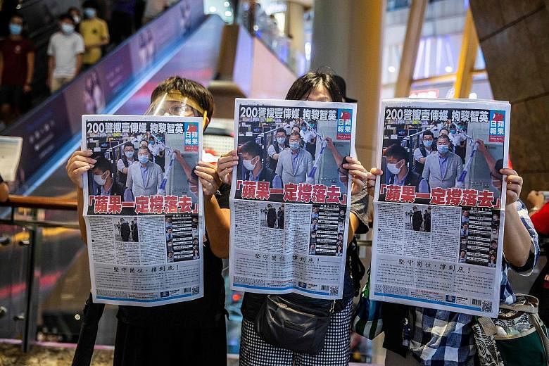 Protesters with copies of the Apple Daily at a mall in Hong Kong on Aug 11, a day after the authorities conducted a search of its newsroom and detained 10 people. The tabloid is unapologetically critical of China.
