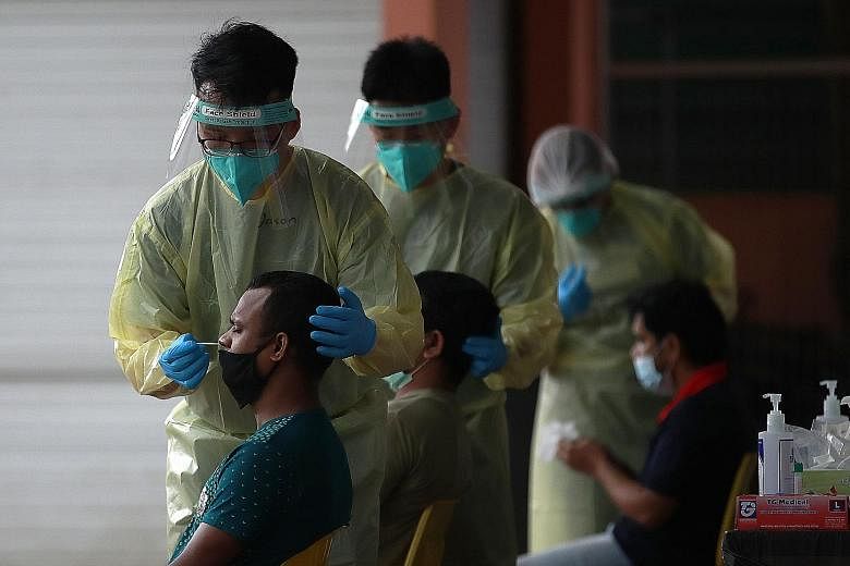 Medical staff conducting a routine swab test for migrant workers in Westlite Juniper dormitory on Tuesday. Recent cases of Covid-19 among foreign workers are being picked up now because the workers are reaching the end of their quarantine periods and