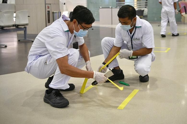Technicians using tape as safe distancing markers in the pharmacy at Singapore General Hospital last Tuesday.