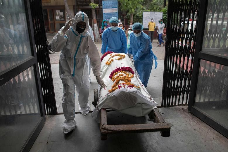 Healthcare workers (in blue) taking the body of a Covid-19 victim, accompanied by a relative, to the Nigambodh Ghat cremation ground in New Delhi on Saturday. As of yesterday morning, India's official death toll stood at 56,706.