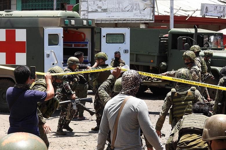 Soldiers carrying away some of the victims after a bomb explosion next to a military truck in the town of Jolo in the Philippines' Sulu province yesterday. At least six soldiers and six civilians were killed in the blast. A second explosion happened 