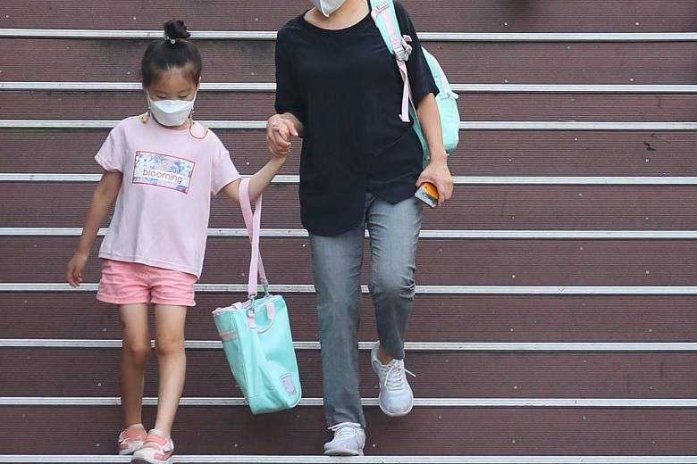 A mother walking her daughter to an elementary school in Seoul yesterday. All students, except for high school seniors, in the cities of Seoul and Incheon and the province of Gyeonggi will take classes online until Sept 11. PHOTOS: AGENCE FRANCE-PRES
