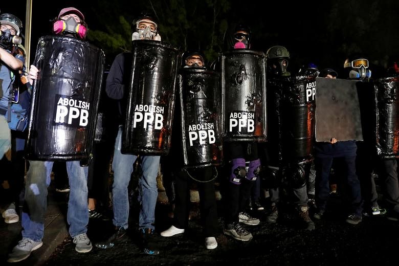 Protesters carrying shields calling for the abolition of the Portland Police Bureau (PPB) during a rally in Portland on Sunday. The police said demonstrators lit fires and attacked officers with lasers, rocks and bottles. PHOTO: REUTERS