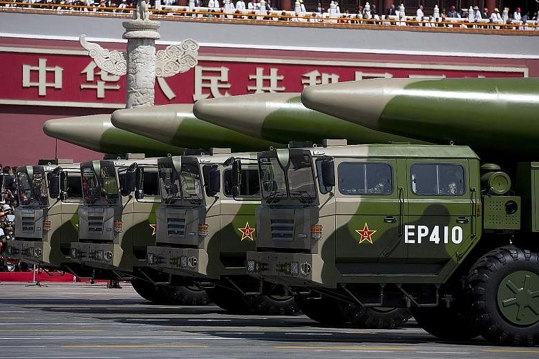 Left: Military vehicles carrying ballistic missiles at a Beijing parade in 2015. Above: An Aug 18 image reportedly showing a Chinese submarine entering an underground base at Hainan island on the South China Sea. PHOTOS: AGENCE FRANCE-PRESSE