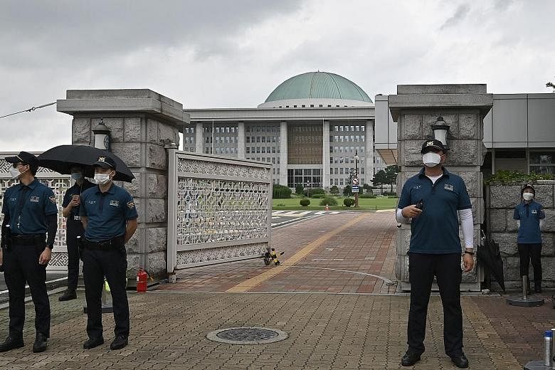 Police officers standing guard at the main gate of the National Assembly in Seoul yesterday, after some lawmakers went into self-quarantine following contact with a positive case. A photojournalist who had covered a ruling party meeting on Wednesday 