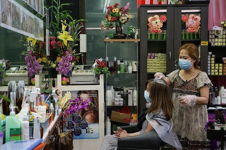 Hair salon owner Jackie Yang tending to a customer at her Lucky Plaza shop yesterday. She said it was quieter yesterday than it was on Friday.