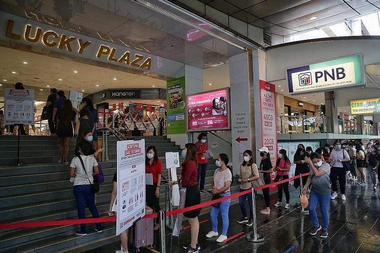 Lucky Plaza (left), which was not crowded inside, just before noon yesterday, while outside (right), people were queueing up to enter the shopping centre in Orchard Road. The restrictions on weekends - which also apply at Peninsula Plaza in North Bri