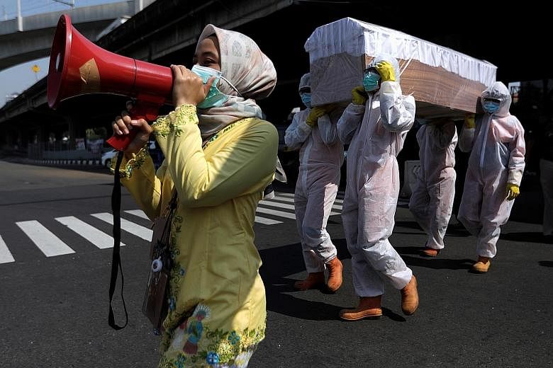 Government workers in protective gear carrying a mock-up of a coffin of a Covid-19 victim on a main road in Jakarta to warn people about the dangers of the virus in the midst of the pandemic. A resurgence of cases will soon put doctors in the positio