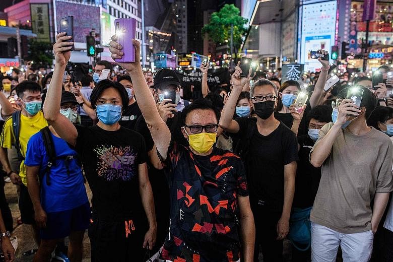 Pro-democracy activists holding up their mobile phone torches as they sang during a rally in Hong Kong's Causeway Bay district in June. Demonstrations have been far fewer and smaller than the mass protests that rocked the Chinese-ruled city in the se
