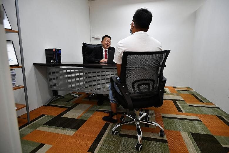 Lawyer Peter Ong Lip Cheng speaking to his client - who is wearing an electronic tag on his left ankle - at his office on Thursday. The rise in the number of accused persons who are released on reduced bail with e-tagging, as well as those placed on 