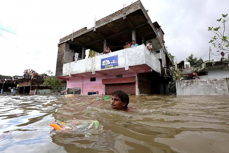 A man trying to save his belongings (top) in the flood-hit area of Hoshangabad (above), 80km from Bhopal, India. Floods around the country were caused by heavy rain during the annual monsoon season, which began around June in South Asia and ends this