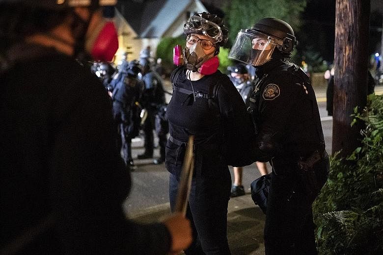 A protester being arrested by a Portland police officer on Sunday. Violence in the Oregon city erupted during a rally involving hundreds of vehicles "caravaning throughout downtown Portland", police said. OregonLive reported "clashes" and "tense mome