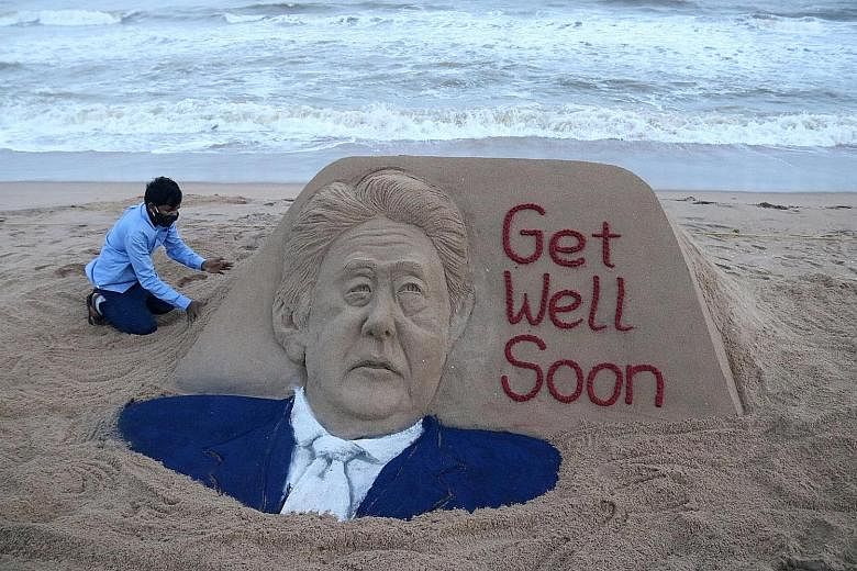 Below: Indian sand artist Sudarsan Pattnaik touching up a sand sculpture of Japanese Prime Minister Shinzo Abe, which he created to wish for the leader's speedy recovery at Puri Beach, about 65km from Bhubaneswar, India, last Saturday. Left: Japan's 