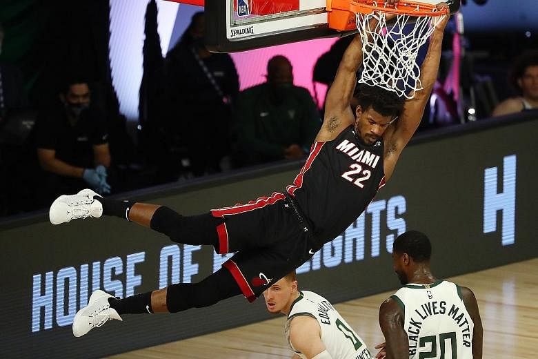 Miami Heat forward Jimmy Butler dunking the ball over Milwaukee Bucks guard Donte DiVincenzo (0) during the third quarter on Monday. The Heat won 115-104 to take a 1-0 lead in their Eastern Conference semi-final series. PHOTO: REUTERS