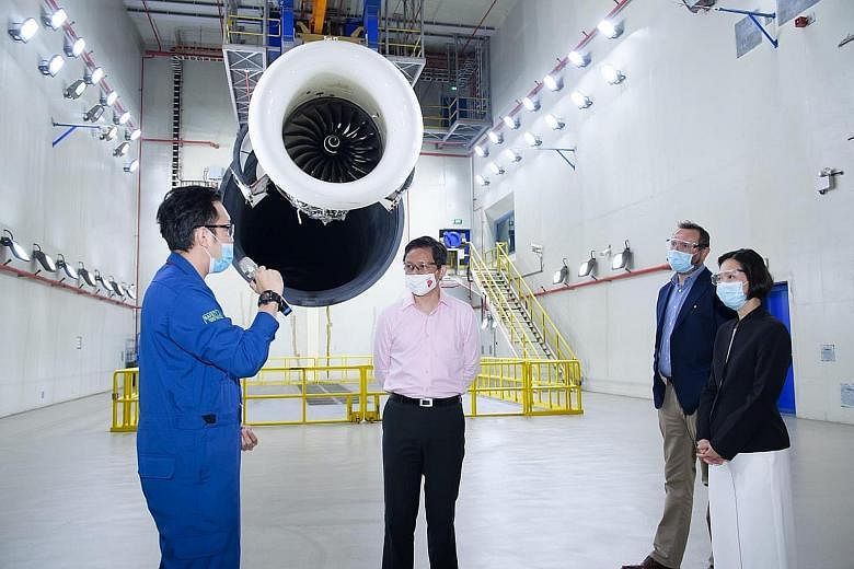 Trade and Industry Minister Chan Chun Sing (centre) and Minister of State for Manpower Gan Siow Huang, accompanied by Singapore Aero Engine Services chief executive Simon Middlebrough, listening to an employee on a visit to the company's facility yes