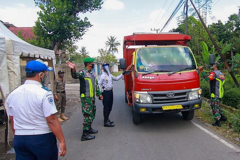 Officials at a checkpoint for a quarantined boarding school in East Java yesterday, after over 600 students tested positive for Covid-19. PHOTO: AGENCE FRANCE-PRESSE