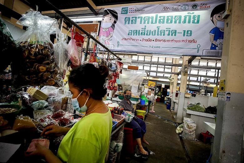 A banner hanging in a Bangkok market yesterday promotes hand washing, the wearing of masks and social distancing to curb the spread of Covid-19. PHOTO: EPA-EFE