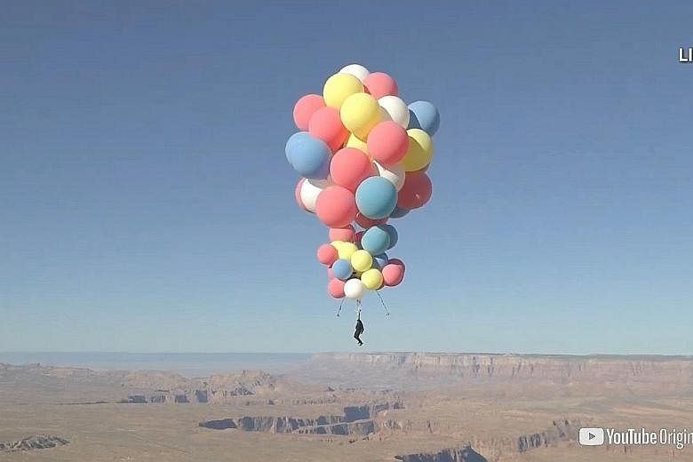 Extreme performer David Blaine flying over the desert in Page, Arizona, on Wednesday, aided by a parachute and a cluster of balloons.