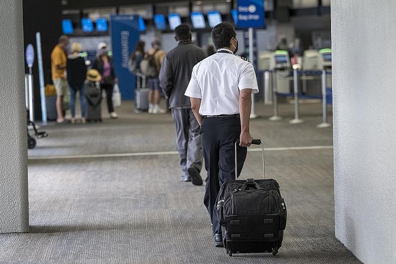 An airline pilot at San Francisco International Airport on Monday. United Airlines and American Airlines are preparing to cut jobs or furlough workers.
