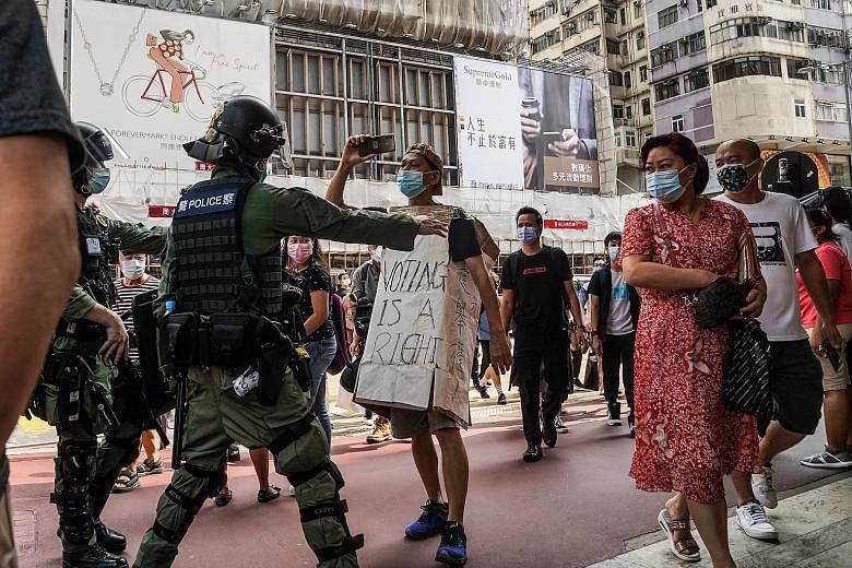 Riot police stopping a demonstrator wearing a sign that reads "Voting is a right" during a protest in Hong Kong yesterday. PHOTO: BLOOMBERG