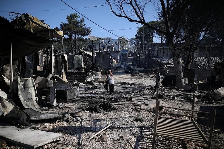 Refugees and migrants walking among destroyed shelters yesterday, following a fire at the Moria camp on the island of Lesbos, Greece. The whereabouts of 35 camp occupants who tested positive for Covid-19 this week were unknown, raising concerns that 
